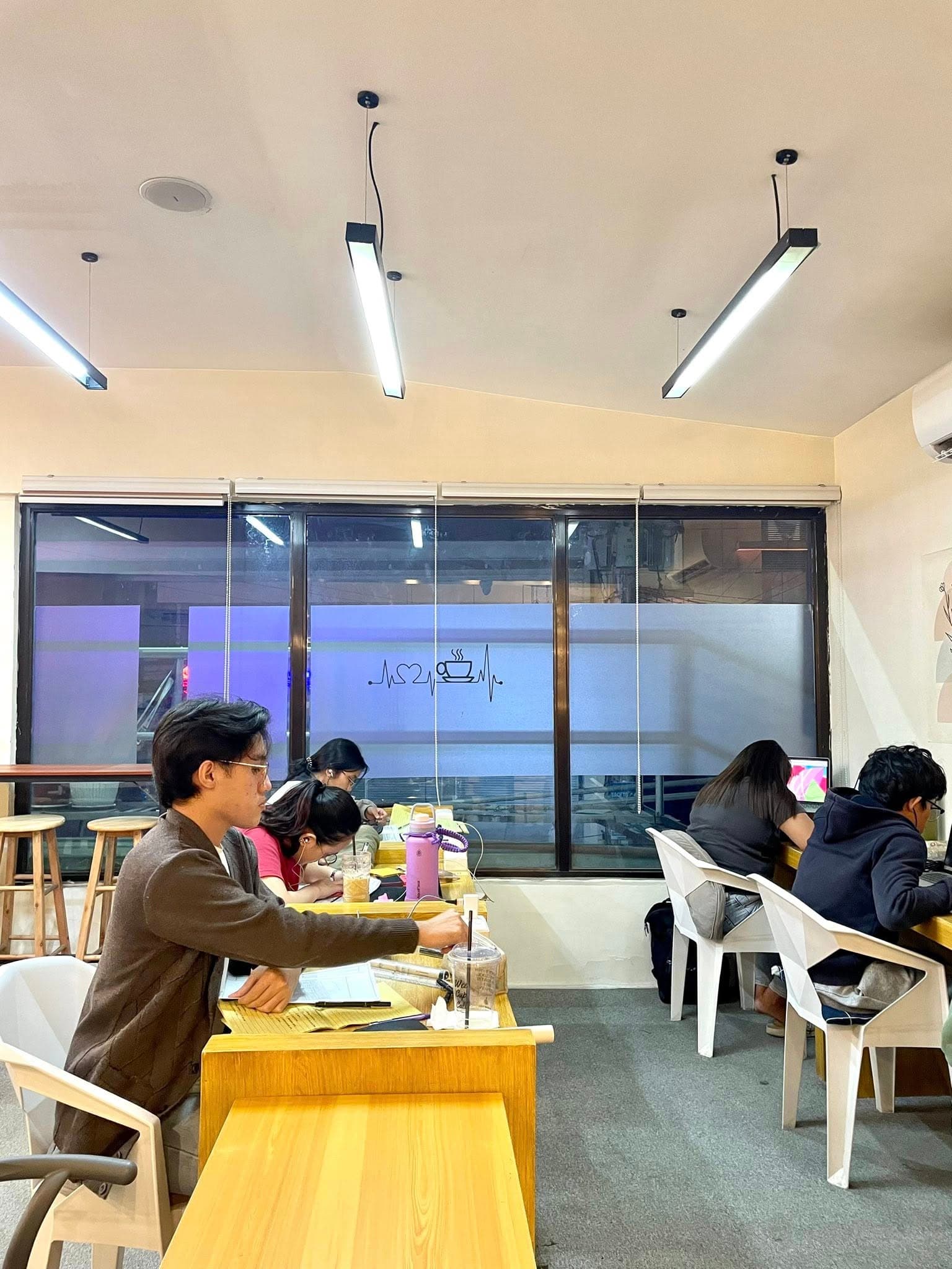 Customers studying at long tables beside the window